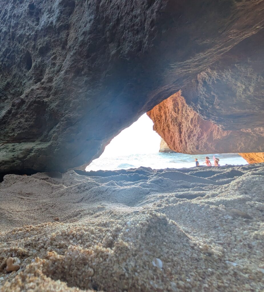 American family who moved to Portugal running on scenic beach with cliffs. 